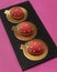 Cakes in strawberry shape on black plate, orange carton and pink background