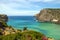 Cala Domestica (Sardinia). Cliff, flowers, a beautiful green and blue sea and cloudy sky