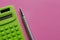 The calculation of the budget, taxes and the cost of the calculator on a pink background. Top view of calculator with pen