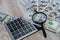 Calculator, american dollars and magnifier on a wooden table