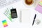 Calculator, euro banknotes, blank notebook on a white desktop next to a coffee mug and a keyboard. Top view, flat layout. Copy the