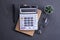 Calculator keypad on a beton floor background. Top view. Copy space.Notebook, pen, glasses And a small artificial plant