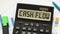 A calculator labeled CASH FLOW lies on financial documents in the office