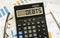 A calculator labeled DEBTS lies on financial documents in the office