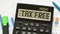 A calculator labeled TAX FREE lies on financial documents in the office