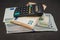 Calculator, stack of dollars and euro banknotes on a black wooden background.