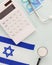 Calculator, stethoscope, Israeli flag and shekels on a blue background