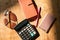 The calculator, sunglasses, working book and smart phone are on the wooden table