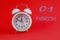 Calendar en March 1: white alarm clock on a crimson background close-up, numbers 01, the name of the month March in English