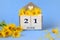 Calendar for June 21: cubes with the number 21 , the name of the month of June in English, a bouquet of yellow daisies, blue