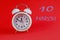 Calendar for March 10: a white alarm clock on a crimson background close-up, the numbers 10, the name of the month March in