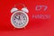 Calendar for March 7: a white alarm clock on a crimson background close-up, the numbers 07, the name of the month March in English