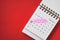 Calendar marked on 14 February with sweet pink arrow and red heart shape around date on grunge red paper background