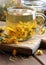 Calendula herbal tea or decoction with flowers in glass cup on wooden rustic board