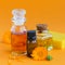 Calendula products. Bottles of cosmetic, aromatic or essential oil and fresh calendula flowers on orange background
