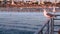 California summertime beach aesthetic, pink sunset. Cute funny sea gull on pier railing. Ocean waves, defocused people and
