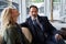 Calm adult couple in outerwear sitting indoors