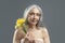 Calm aged european lady with gray hair hold bouquet of yellow flowers, enjoy spring, freshness