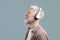 Calm albino guy enjoying music through wireless headphones with closed eyes and smile, listening favorite melodies or