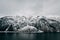 calm alpine lake and snow-covered mountains at cloudy day,