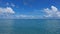 Calm aquamarine ocean and azure sky with cumulus clouds