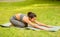Calm Asian woman doing child yoga pose on sports mat at green park