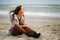 Calm beautiful woman sit alone on a beach sand and look at the water