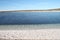 Calm blue water with sandy beach and green horizon