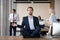 Calm businessman in suit meditating in office on work desk