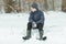 Calm child sitting down after playing in the snow