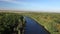 The calm clean river flows between green trees. Aerial view