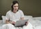 Calm, concentrated woman in pajamas working with a laptop in bed. Concept of self-isolation during a virus epidemic and