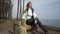 Calm confident beautiful woman with closed eyes sitting on tree trunk on river bank smiling. Wide shot portrait of