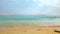 Calm day at Ein Bokek Dead Sea beach, blue green water, sun shade shelter near, sun shines on sand beach foreground