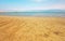 Calm day at Ein Bokek Dead Sea beach, blue green water, sun shade shelter near, sun shines on sandy beach shore