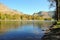 The calm expanse of a mountain river and a suspension bridge across it, surrounded by high mountains