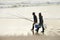 Calm, fishing and men walking on beach together with cooler, tackle box and holiday conversation. Ocean, fisherman and