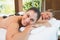 Calm friends lying on massage tables with hot stones on their backs