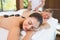 Calm friends lying on massage tables with hot stones on their backs