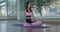 Calm girl sits in lotus pose inside, great model meditates on mat in light gym