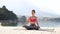 Calm girl sitting in lotus pose on stone paving by the sea