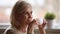 Calm happy old woman sitting alone holding cup enjoying coffee