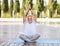 Calm happy senior man sitting in lotus pose on mat during morning meditation in park