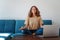 Calm healthy young woman taking break  with eyes closed sit on blue sofa with laptop,  breathing exercise at home feel stress,