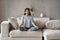 Calm Hispanic woman practice yoga sitting on sofa