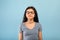 Calm Indian teen girl posing with closed eyes, meditating or praying to God over blue studio background