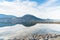 Calm lake reflecting blue sky and clouds with breakwater and mountains in distance