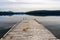 Calm lake with reflections of mountains and sky and a wooden dock in the foreground