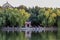 The calm lake reflects green trees and red arched doors