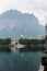 Calm morning coastline with buildings, mountain with clouds in background.